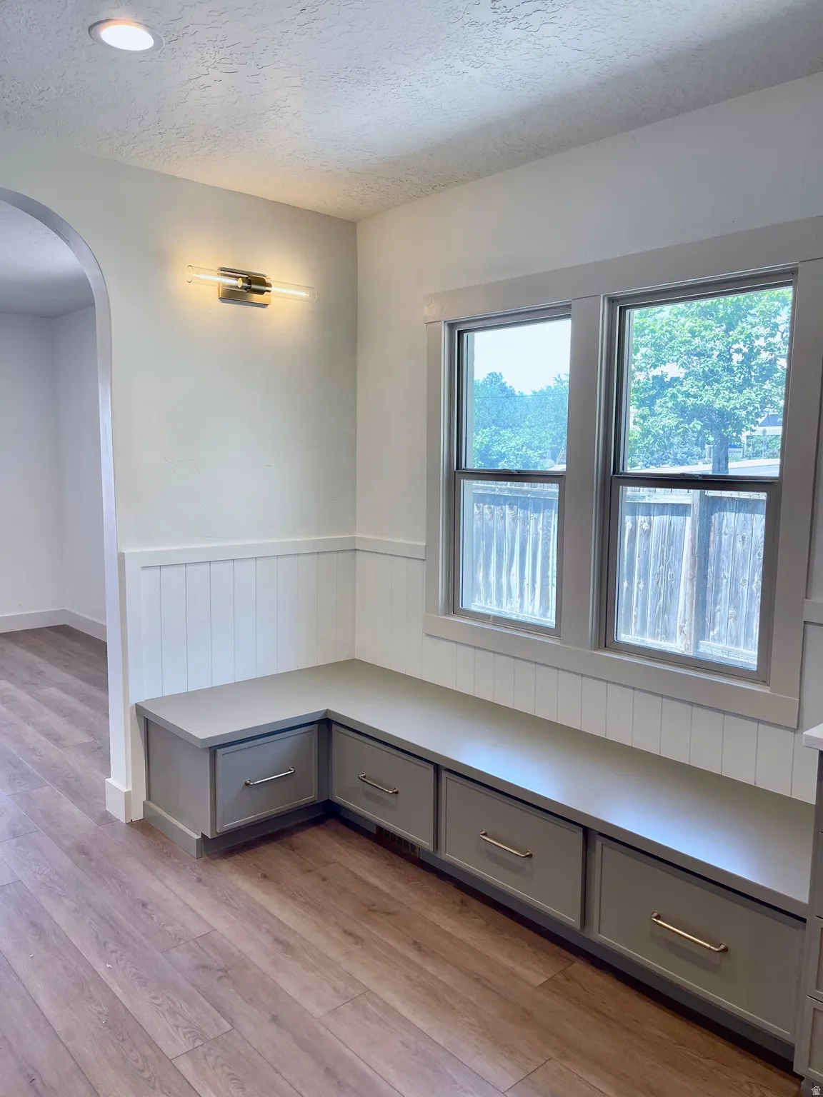 Built-in corner bench seating with drawer storage, featuring a window and wainscoting