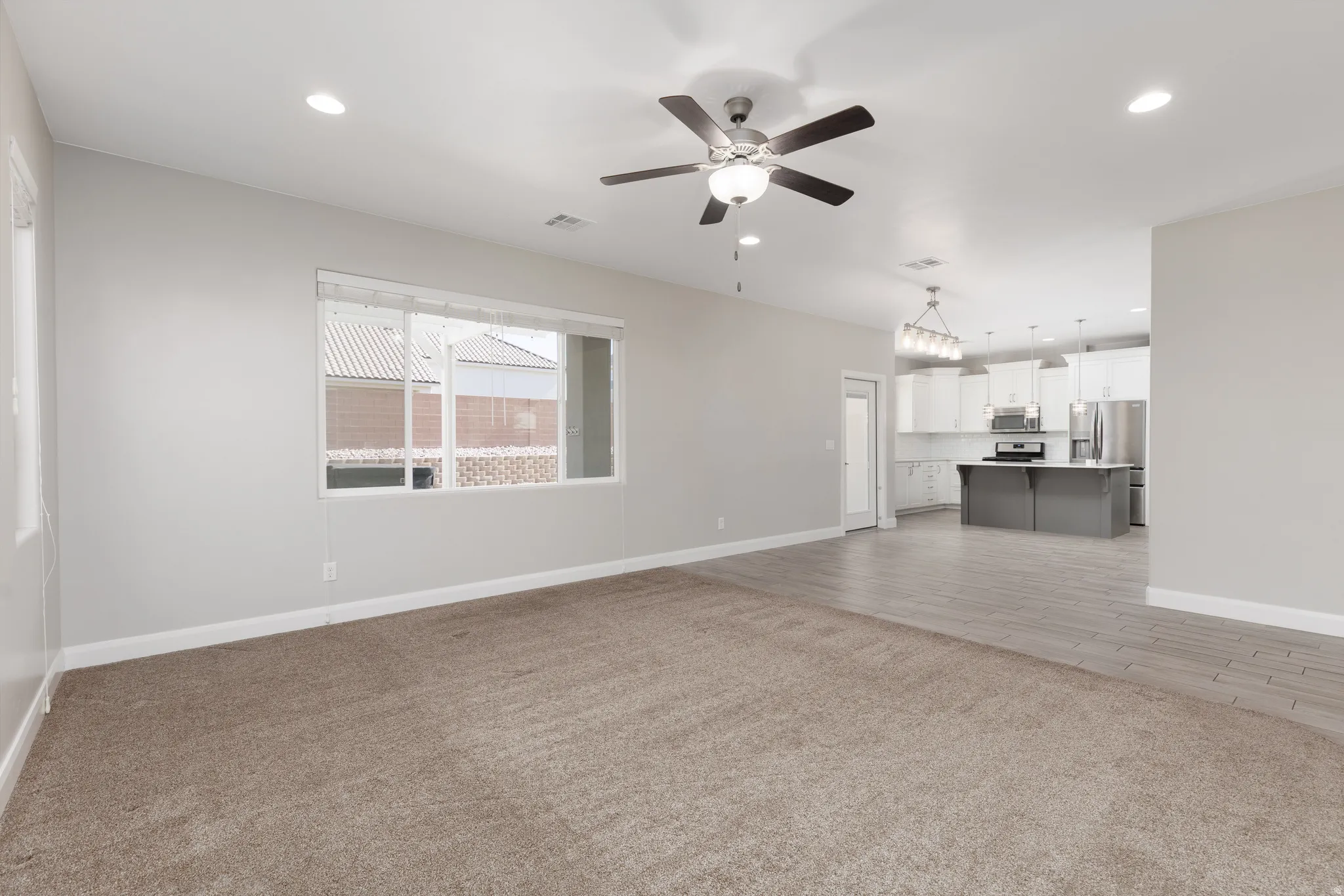 Bright living space featuring neutral paint, carpet flooring, a ceiling fan, and recessed lighting