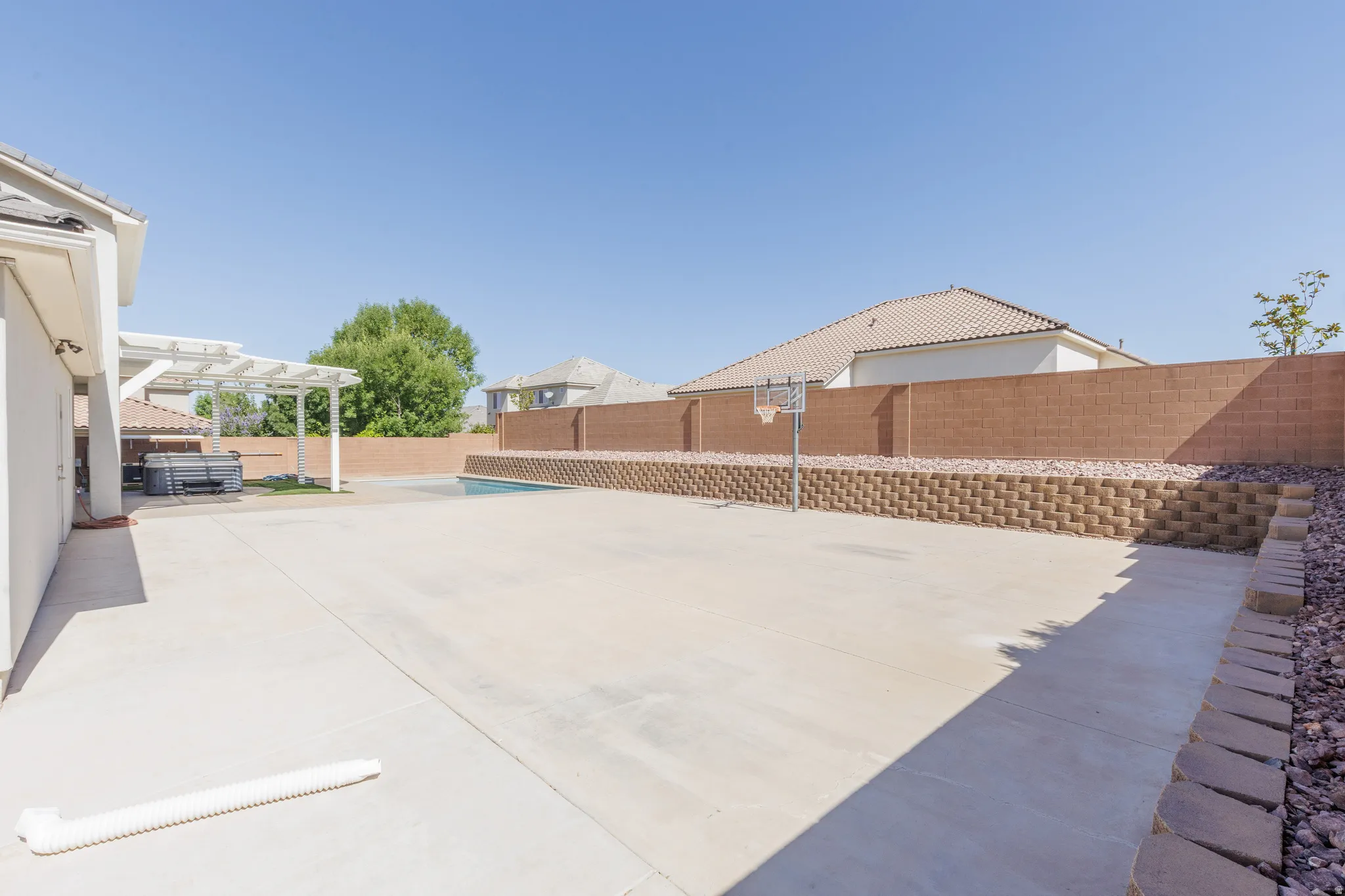 Expansive concrete patio area featuring a white pergola structure