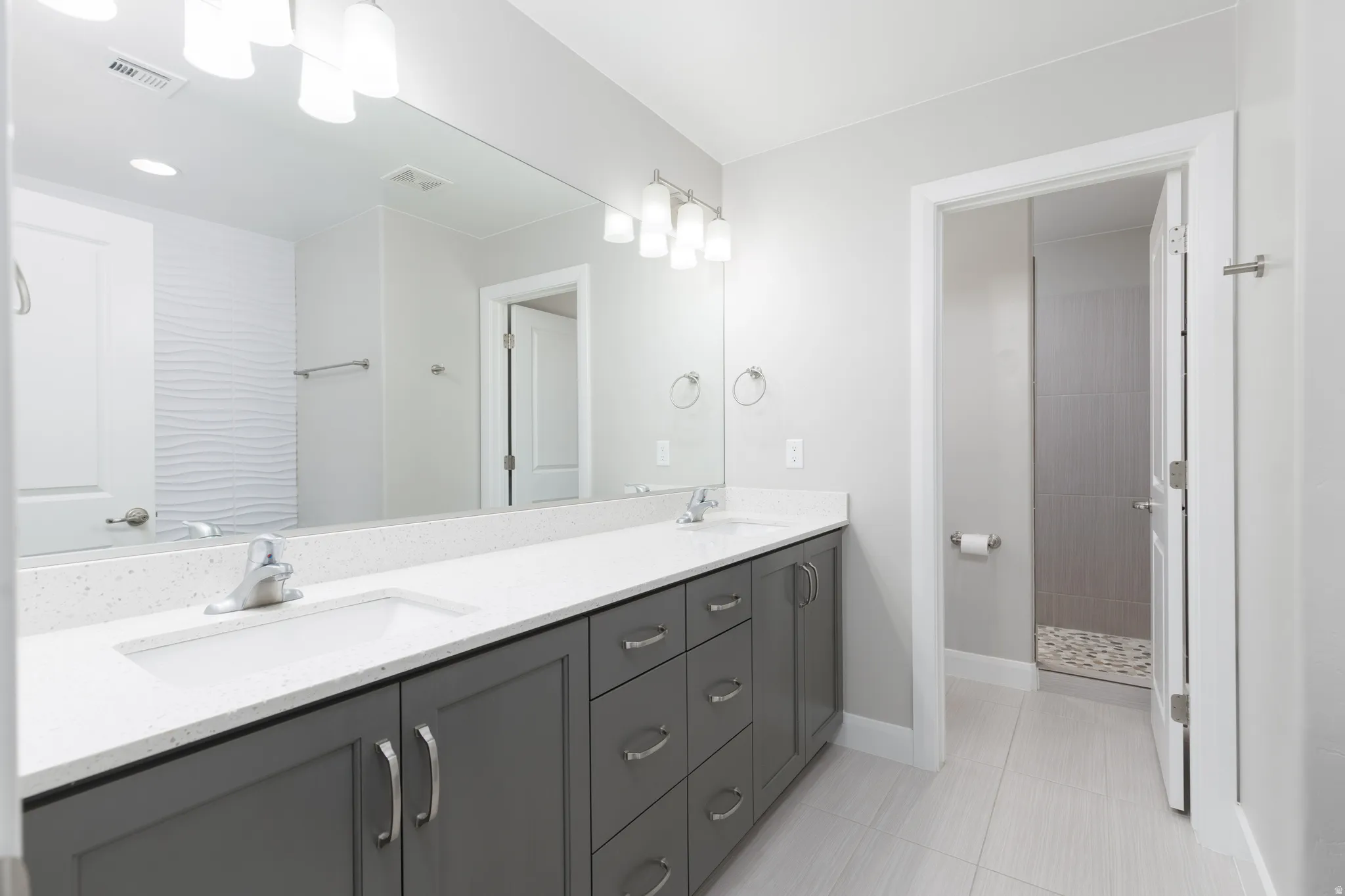 Dual vanity with undermount sinks, stone-finish countertop, and dark gray cabinetry