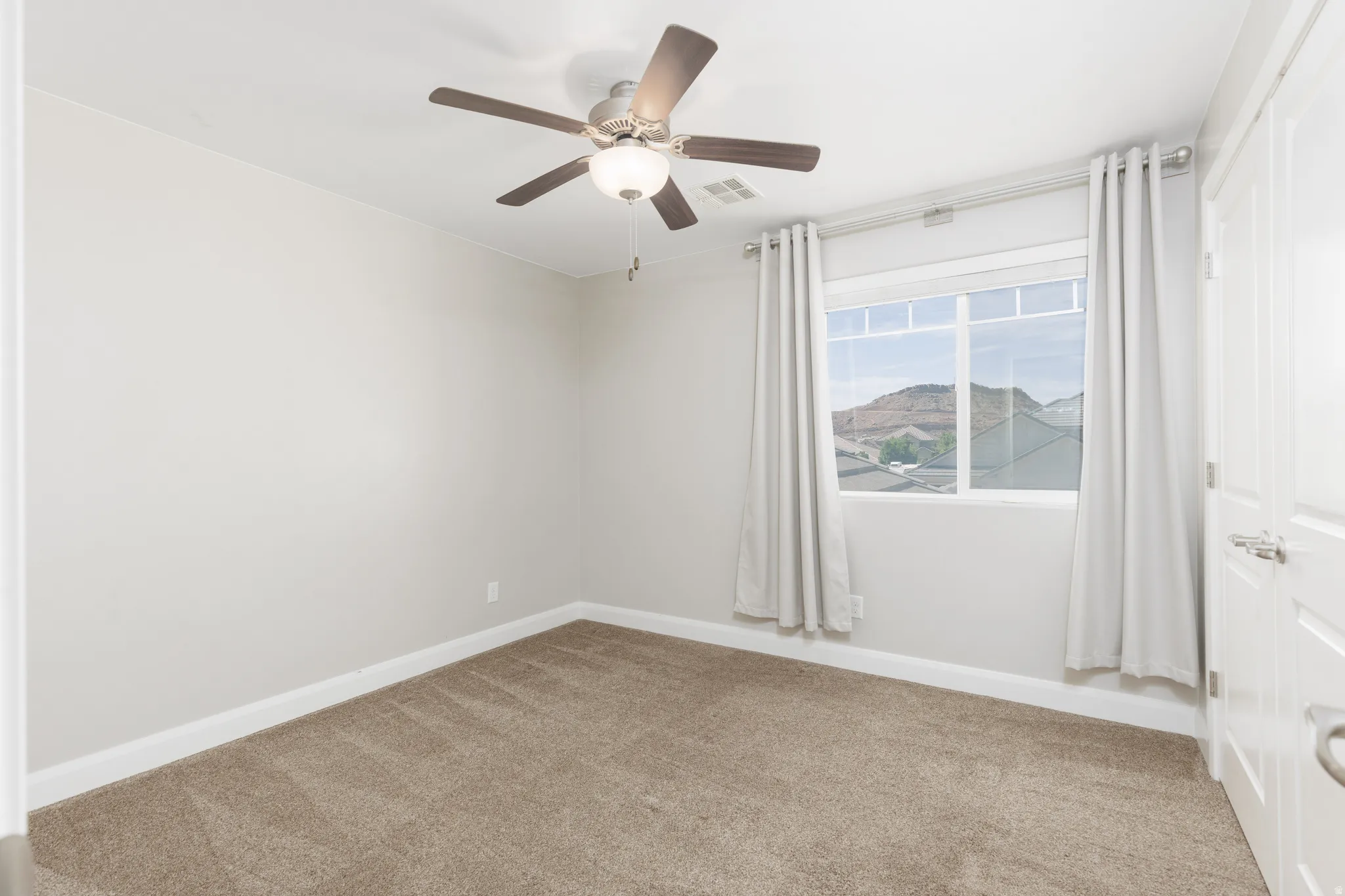 Carpeted room featuring a ceiling fan with integrated lighting, a window with mountain scenery, and white trim