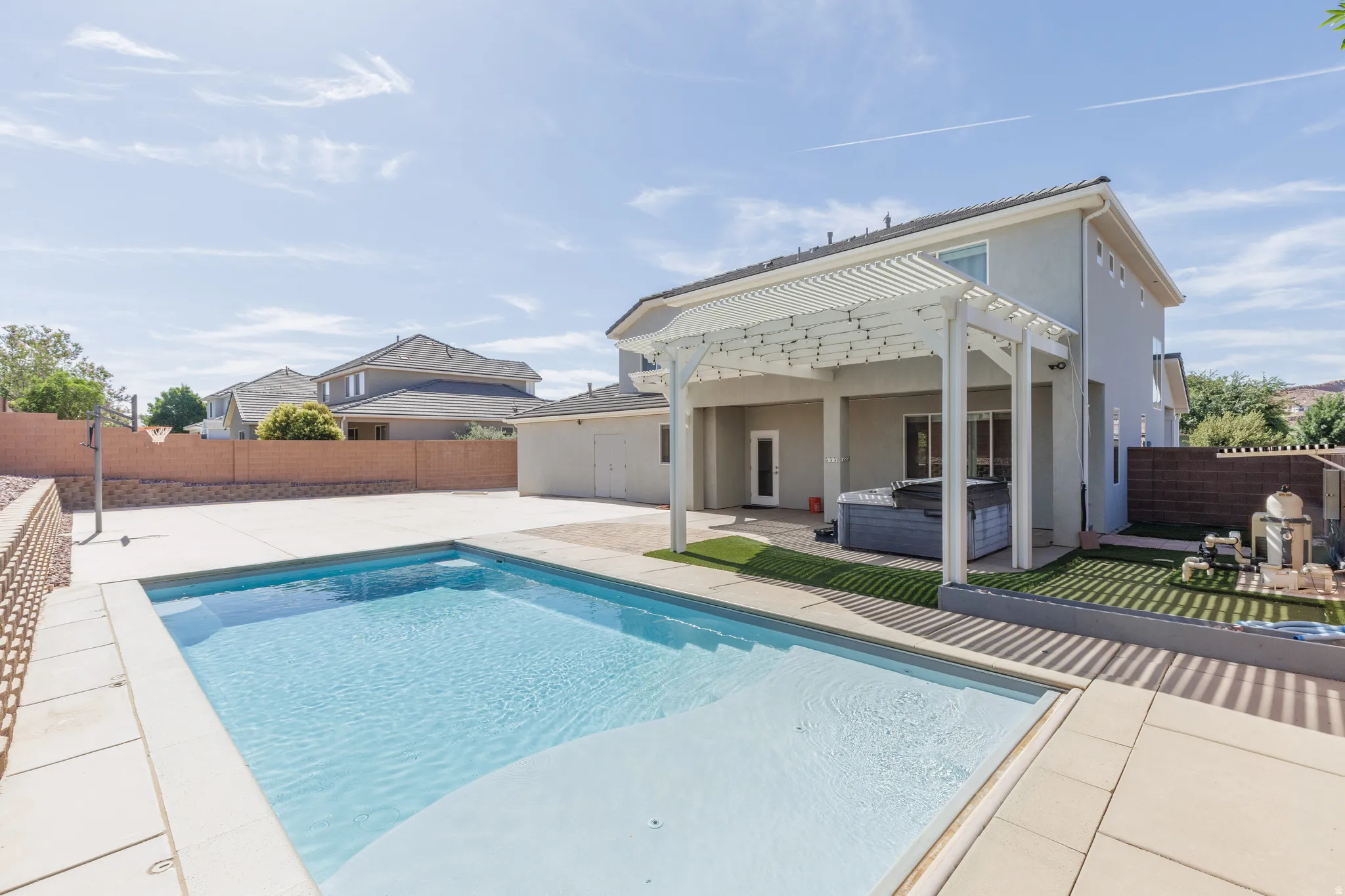 Backyard featuring an in-ground swimming pool with integrated steps, surrounded by concrete decking