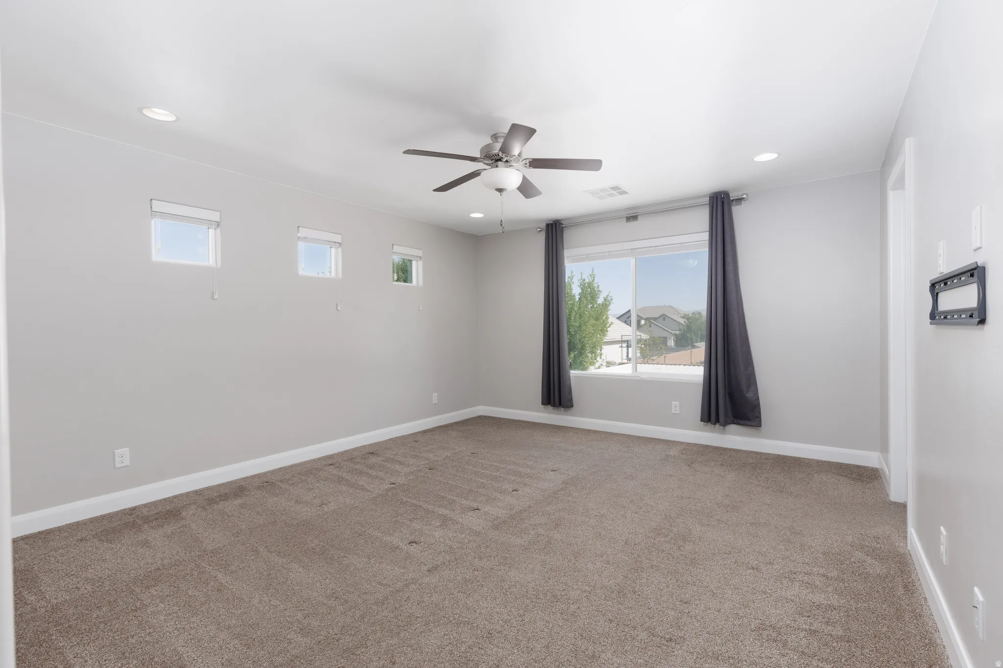 Expansive room featuring neutral-toned carpet, recessed lighting, and a ceiling fan