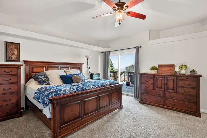 Recessed ceiling with an overhead fan light fixture, sliding glass door with exterior access, light-toned carpet flooring, and white painted walls