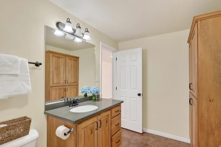 Bathroom featuring a wood vanity with an integrated sink, a gray countertop, and a large wall mirror