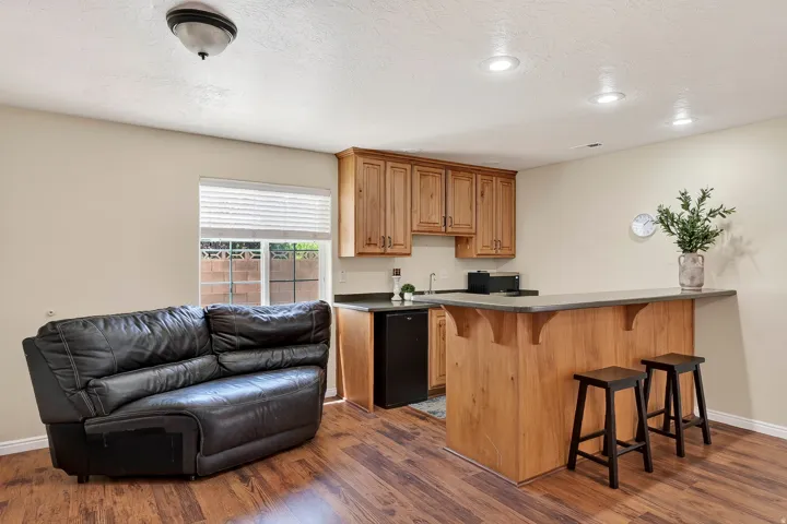 Entertainment area featuring wood-finish flooring, a built-in wet bar with wood cabinetry, a bar-height counter, and recessed lighting