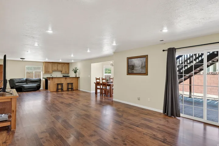 Spacious open-concept living area featuring wood-finish flooring, recessed lighting, and a sliding glass door for exterior access
