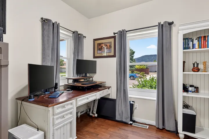 Dedicated room featuring wood-finish flooring, two large windows with mountain scenery, and a built-in white shelving unit
