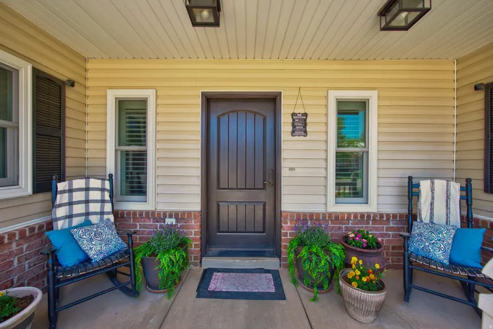 Covered front porch featuring a dark wood-finish entry door with arch detailing