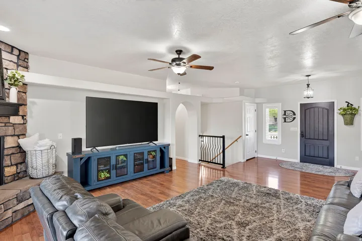 Spacious living area featuring wood-finish flooring, a stone-faced fireplace, and an arched entry