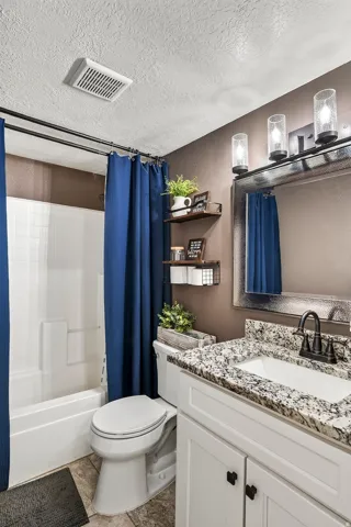 Bathroom featuring a white vanity with a granite-style countertop, undermount sink, and matte black faucet