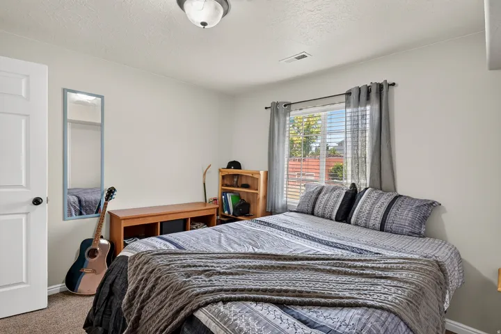 Neutral wall paint, ceiling-mounted light fixture, and a window with blinds and drapes