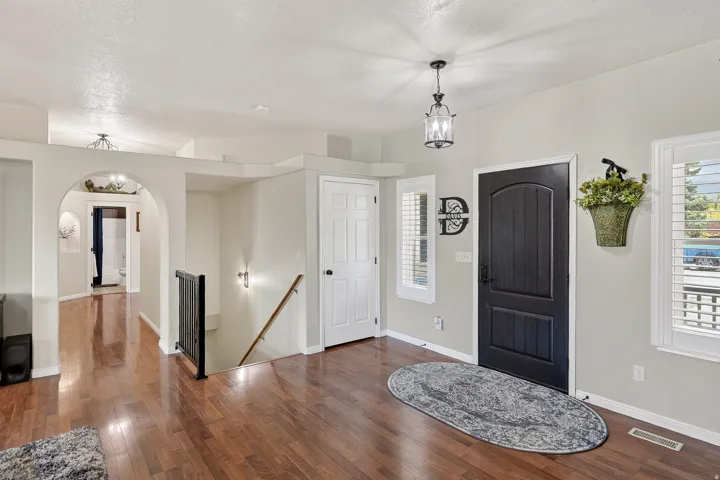 Entryway featuring wood-finish flooring, a dark paneled door with sidelight windows, and a decorative pendant light fixture