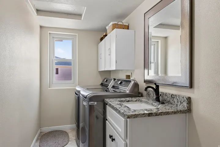 Laundry area featuring a vanity with a granite-style countertop, undermount sink, and matte black faucet