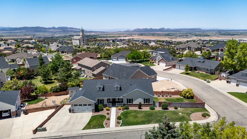 Suburban home featuring a two-car garage, dormer windows, landscaped front yard, concrete driveway, and a residential neighborhood setting