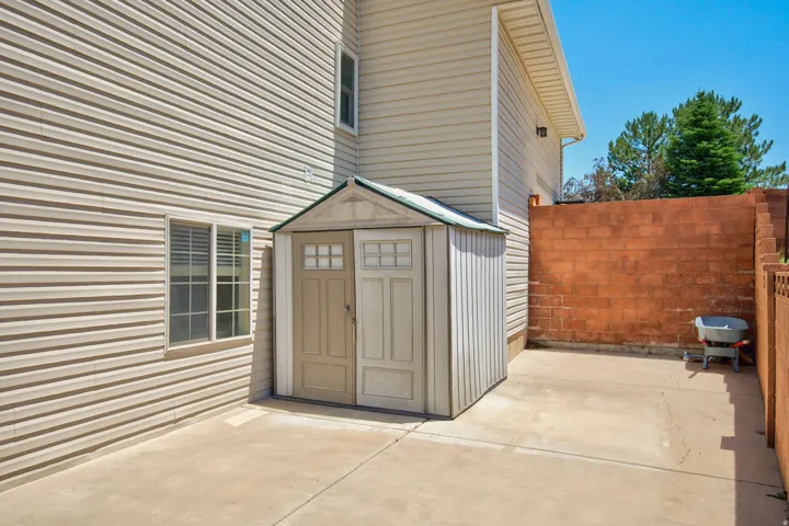 Exterior storage shed on a concrete pad, featuring double doors with decorative window panes