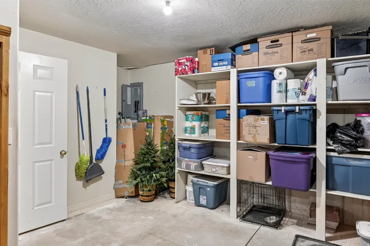 Utility area featuring extensive built-in shelving, a white paneled door, and a concrete floor