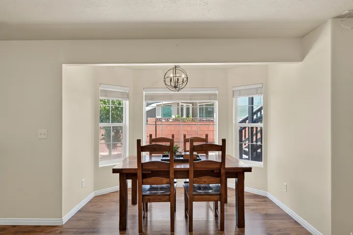 Recessed dining nook featuring a bay window, wood-finish flooring, and a spherical chandelier