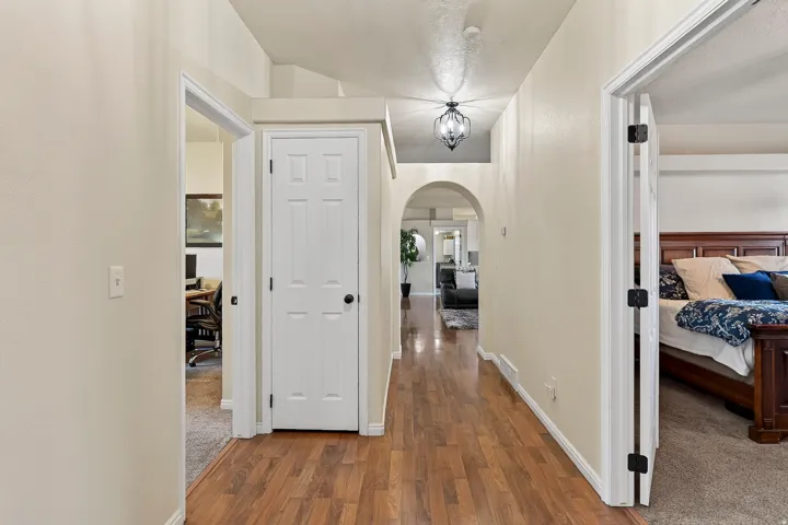 Hallway featuring wood-finish flooring, an arched entryway, and a decorative ceiling light fixture