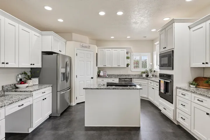 Kitchen featuring white cabinetry, granite countertops, a central island, recessed lighting, and stainless steel appliances