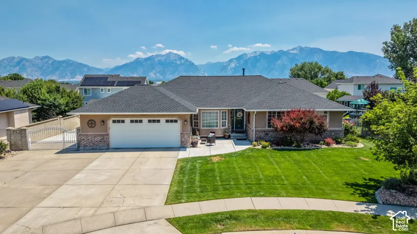Single-story residence featuring a two-car garage, manicured front lawn, and mature landscaping