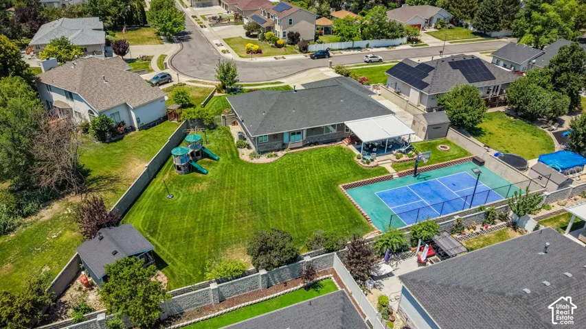 Expansive green lawn with a sports court, covered patio, and mature landscaping