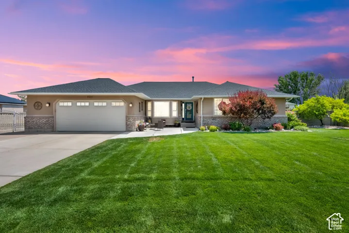 Ranch-style exterior with a two-car garage, partial stone facade, and a dark asphalt shingle roof
