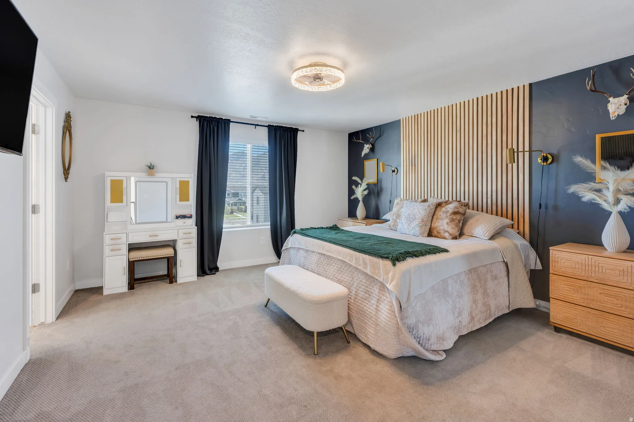 Spacious bedroom featuring light neutral carpeting, a window with dark drapery, and a decorative accent wall with vertical wood paneling