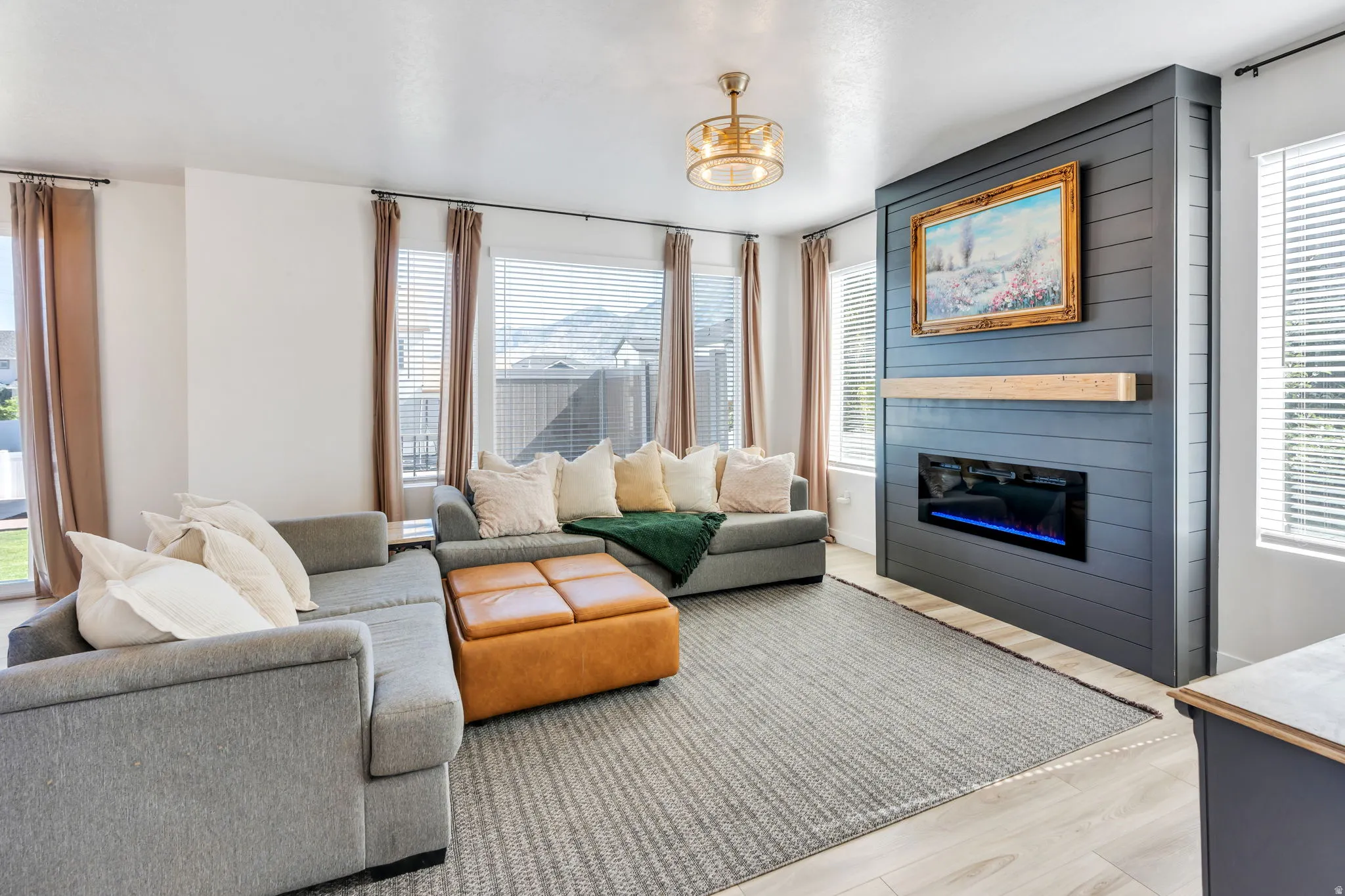 Living area featuring a shiplap accent wall with an electric fireplace and a natural wood mantel