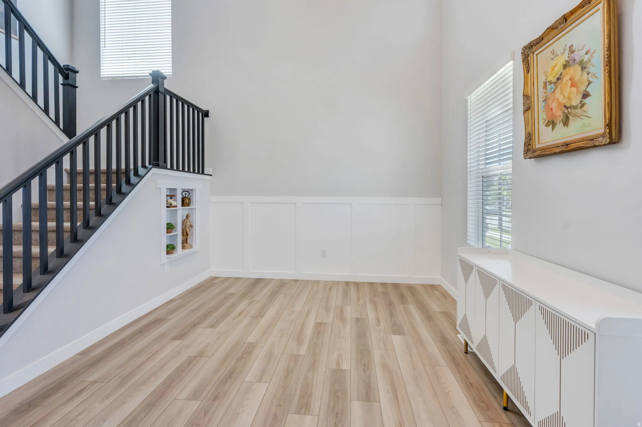 Entryway featuring wood-finish flooring and a staircase with dark balusters