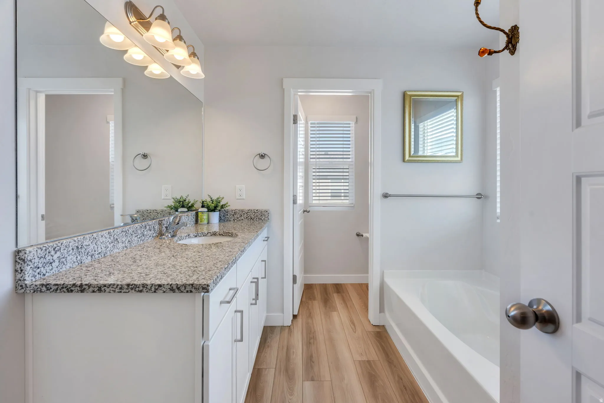 Bathroom featuring a white vanity with brushed nickel pulls, a granite-finish countertop, and an integrated white sink