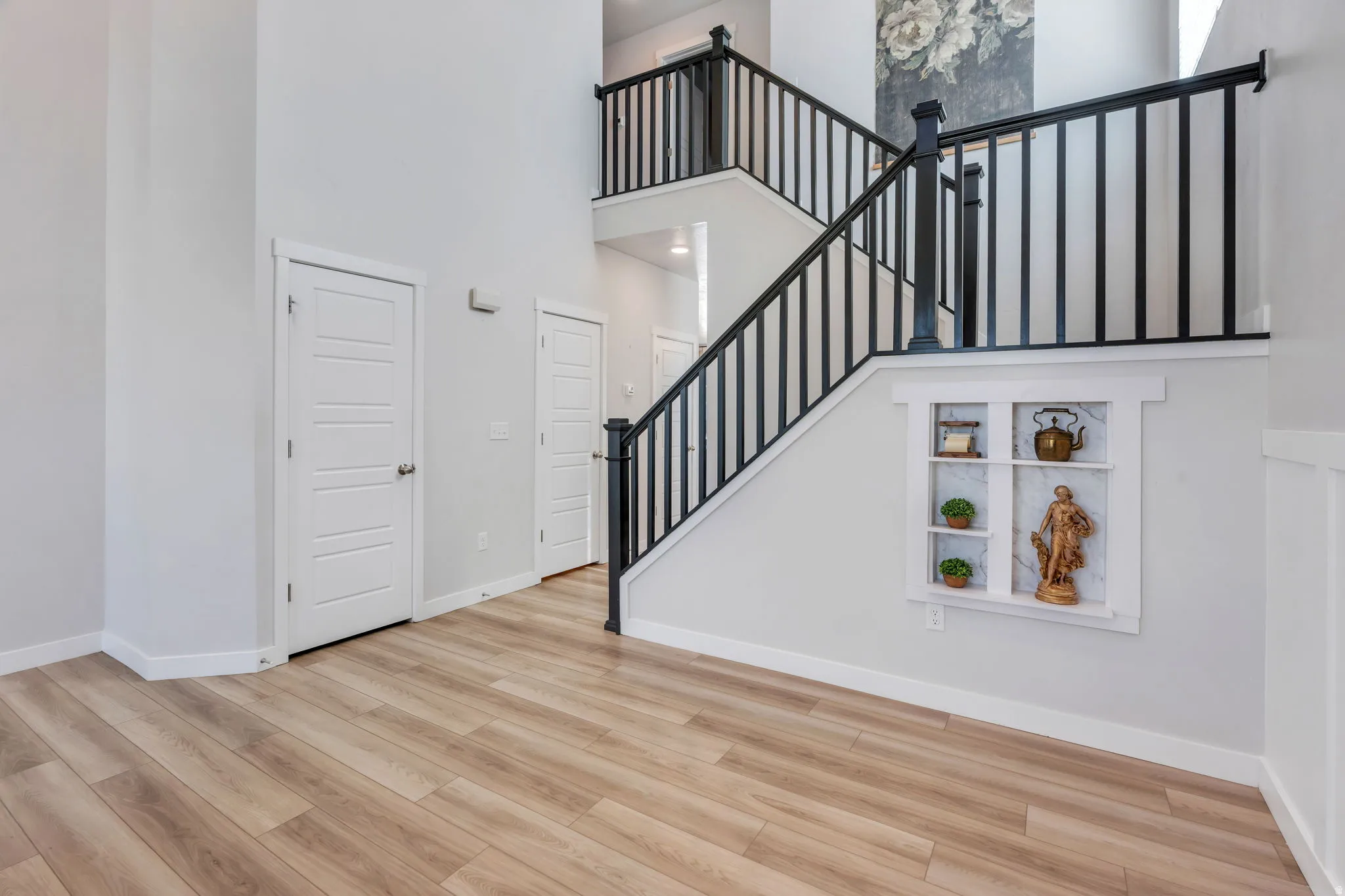 Staircase with black balusters and wood-finish handrails, complemented by a built-in wall niche with a marble-look back panel