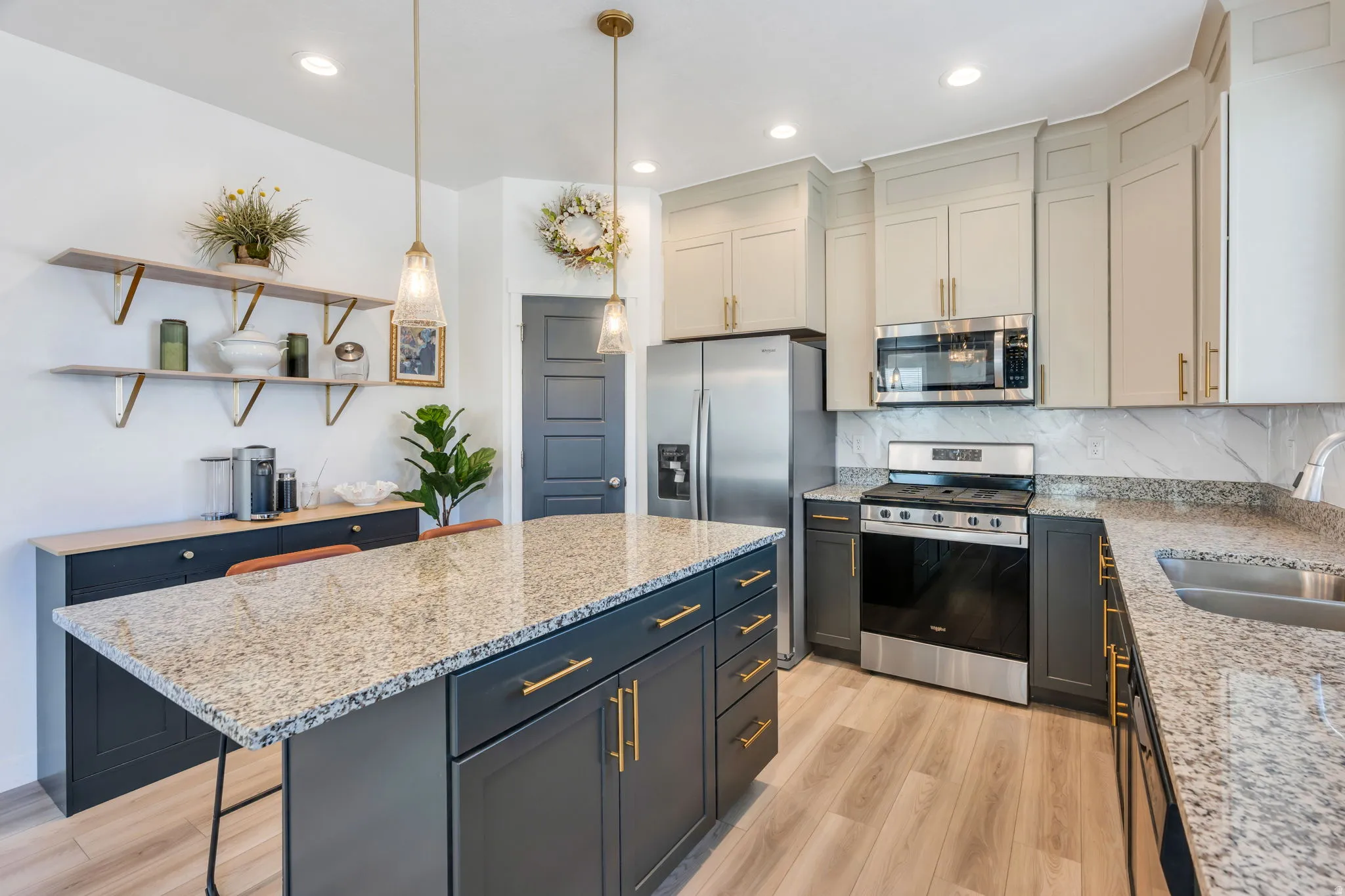 Modern kitchen featuring light wood-finish flooring and a central island with a speckled stone countertop