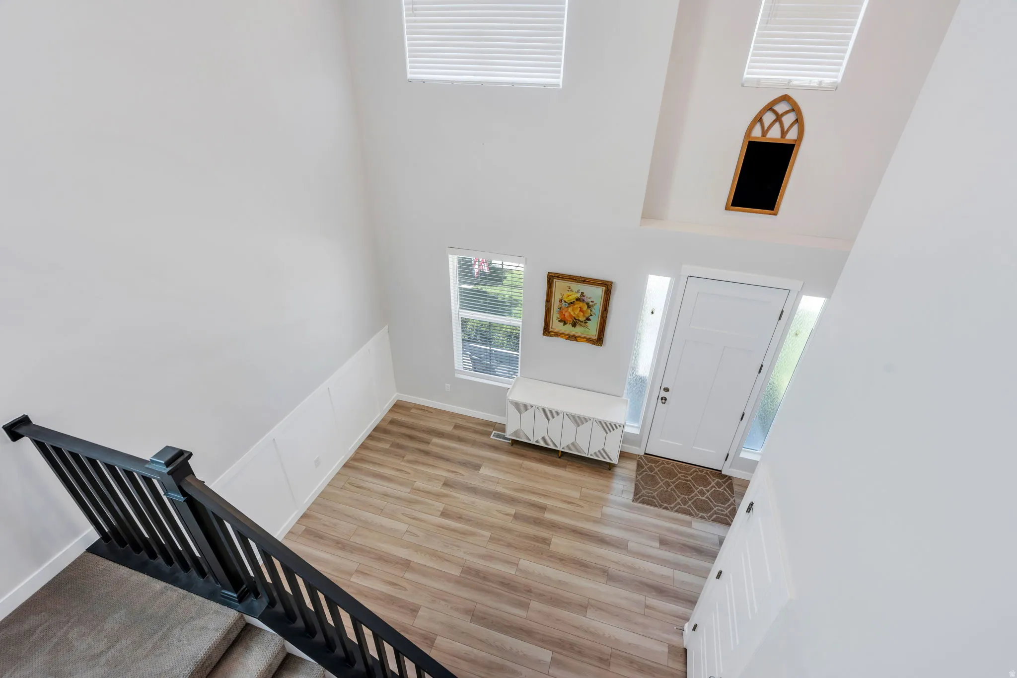 Two-story entry foyer featuring wood-finish flooring, a white front door with sidelights, and a high ceiling with clerestory windows