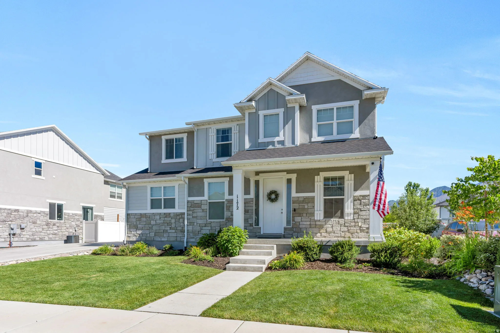 Two-story home with a stone and siding facade, featuring a front porch with square columns