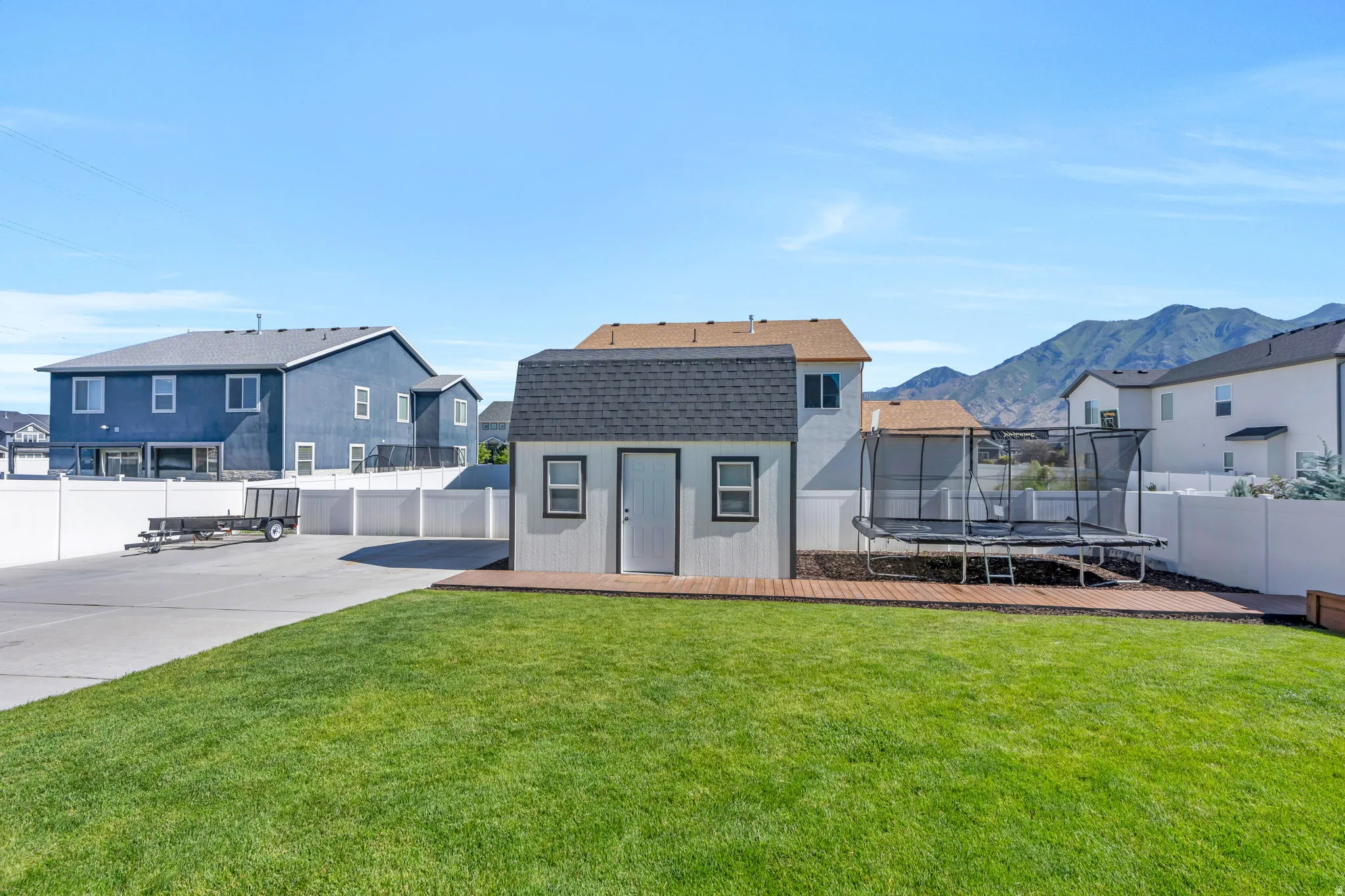 Expansive green lawn with a two-story shed featuring a gambrel roof and dark shingle siding