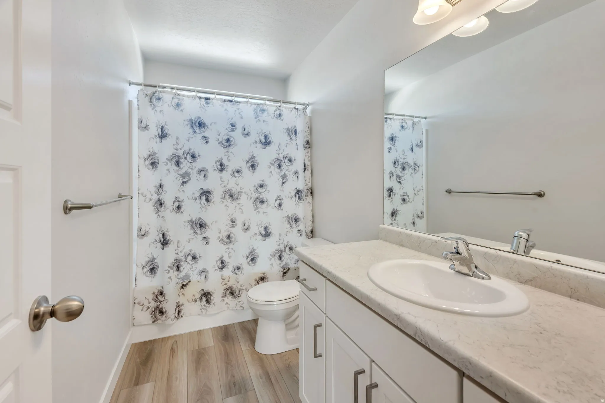 Bathroom featuring a single vanity with an integrated sink, chrome faucet, and a large wall-mounted mirror