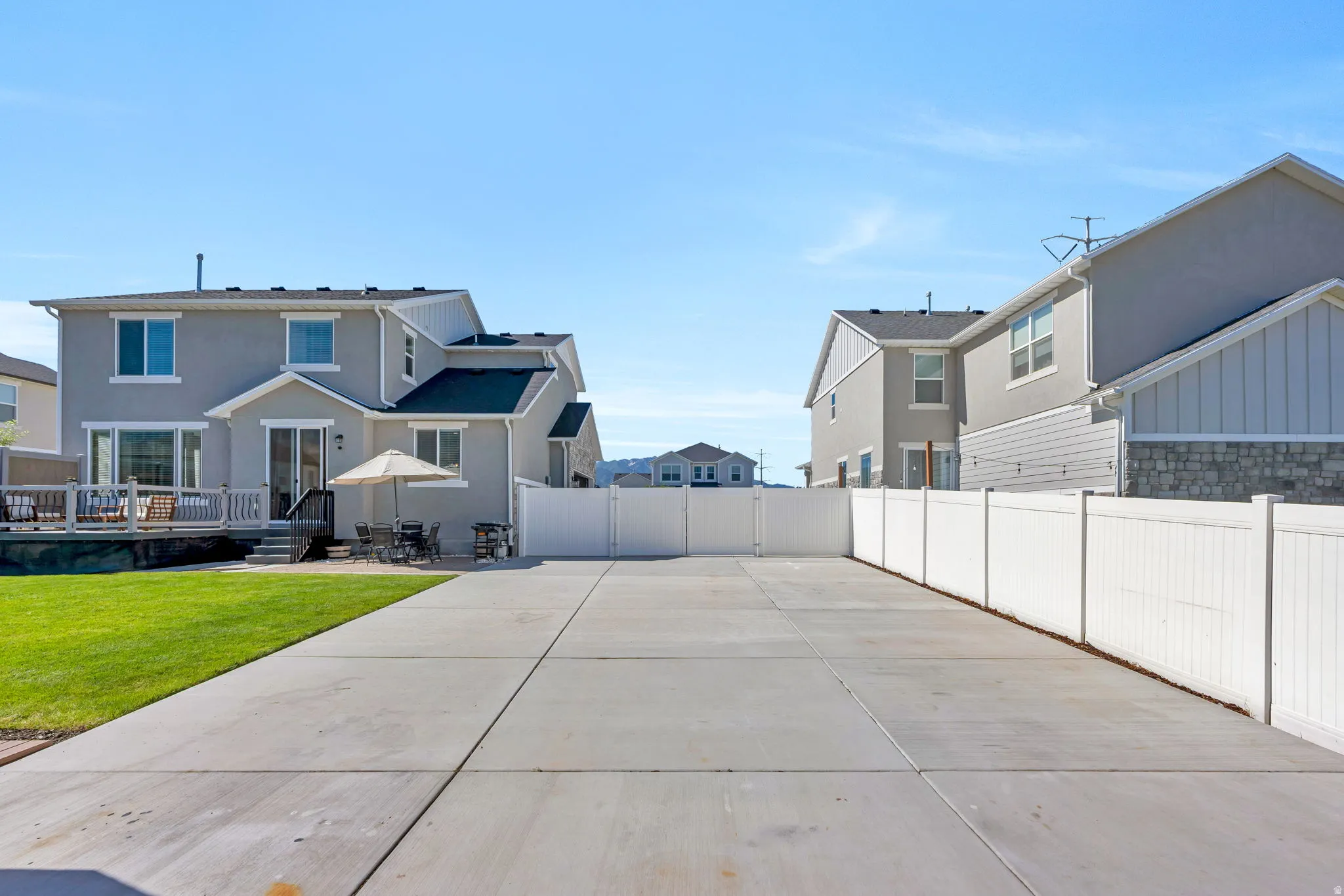 Spacious concrete patio area with a white vinyl privacy fence
