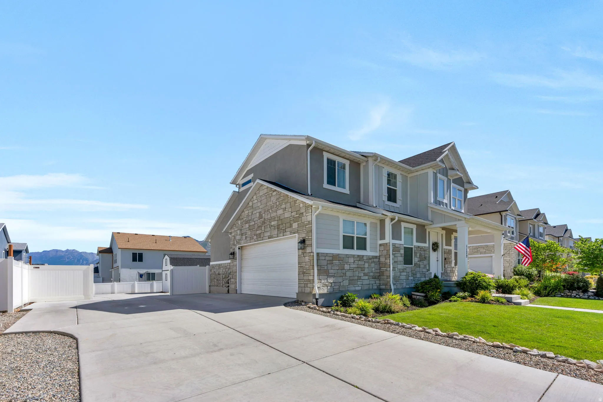 Two-story residence featuring light gray siding and stone veneer accents