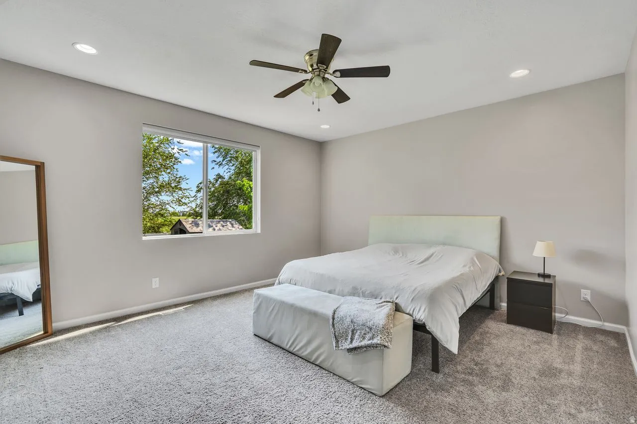 Carpeted room with a large window, recessed lighting, and a ceiling fan
