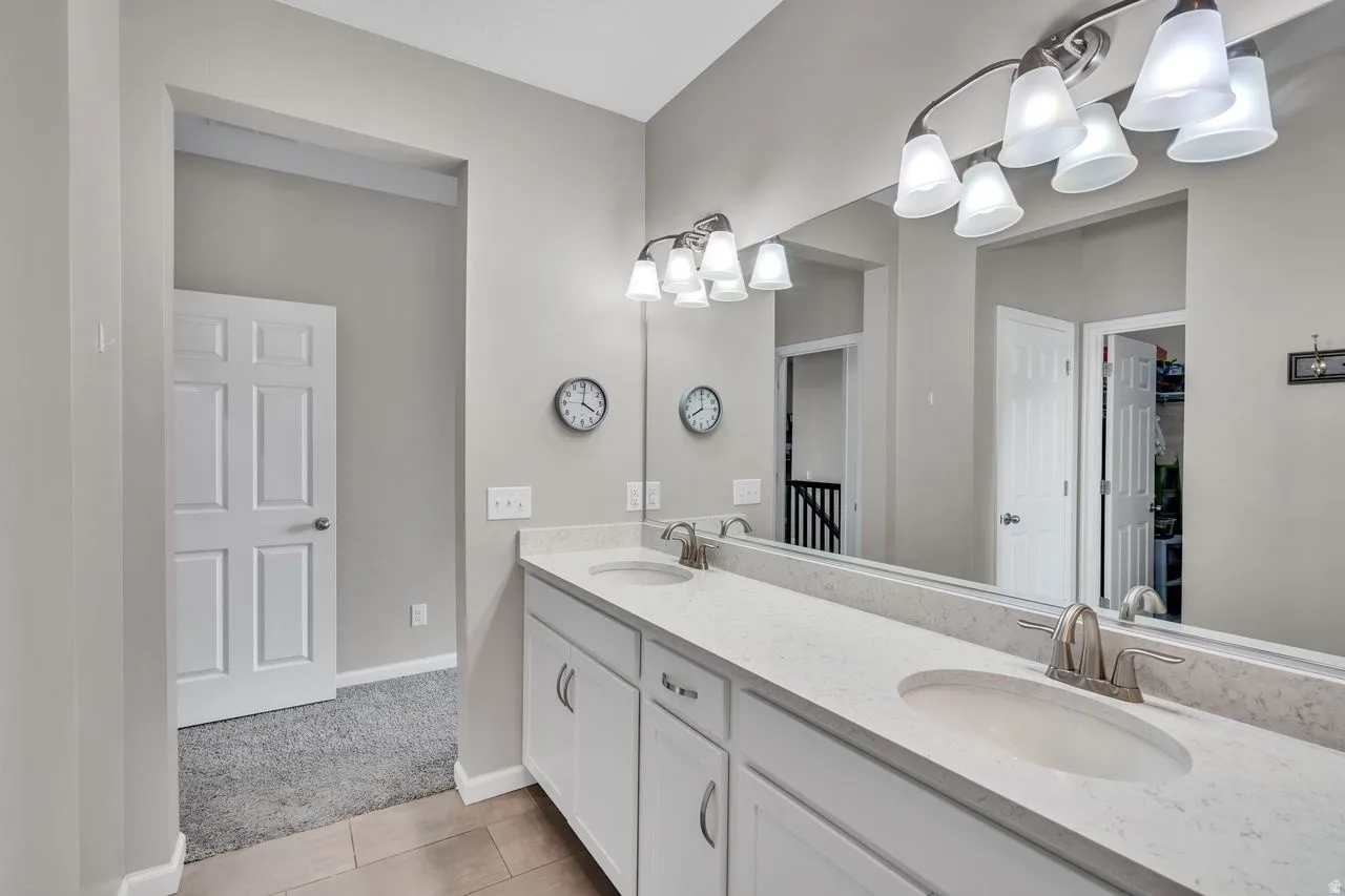 Dual vanity featuring white cabinetry, light-toned countertops, and brushed nickel fixtures