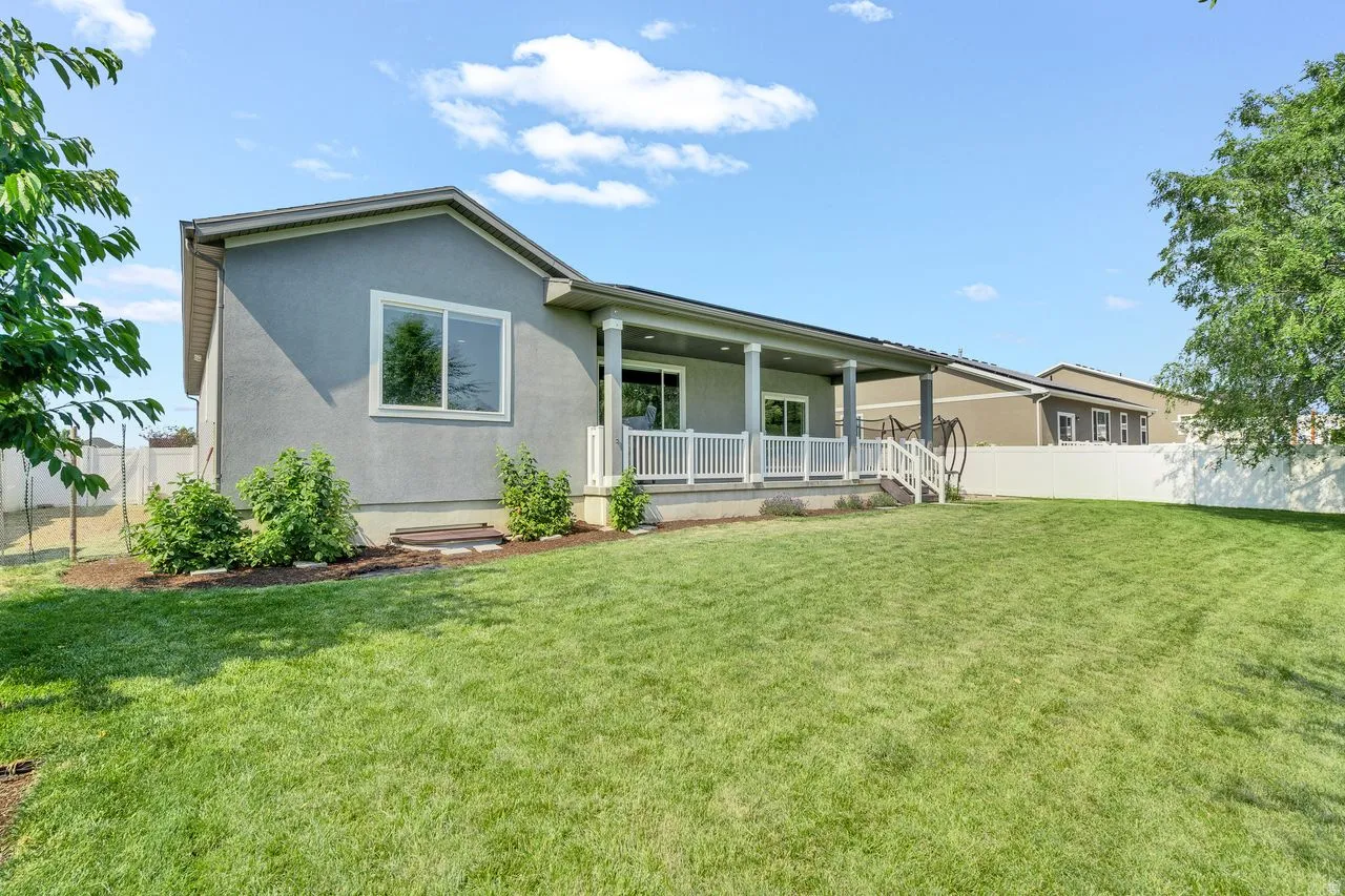 Expansive green lawn with a covered patio featuring white railings and columns