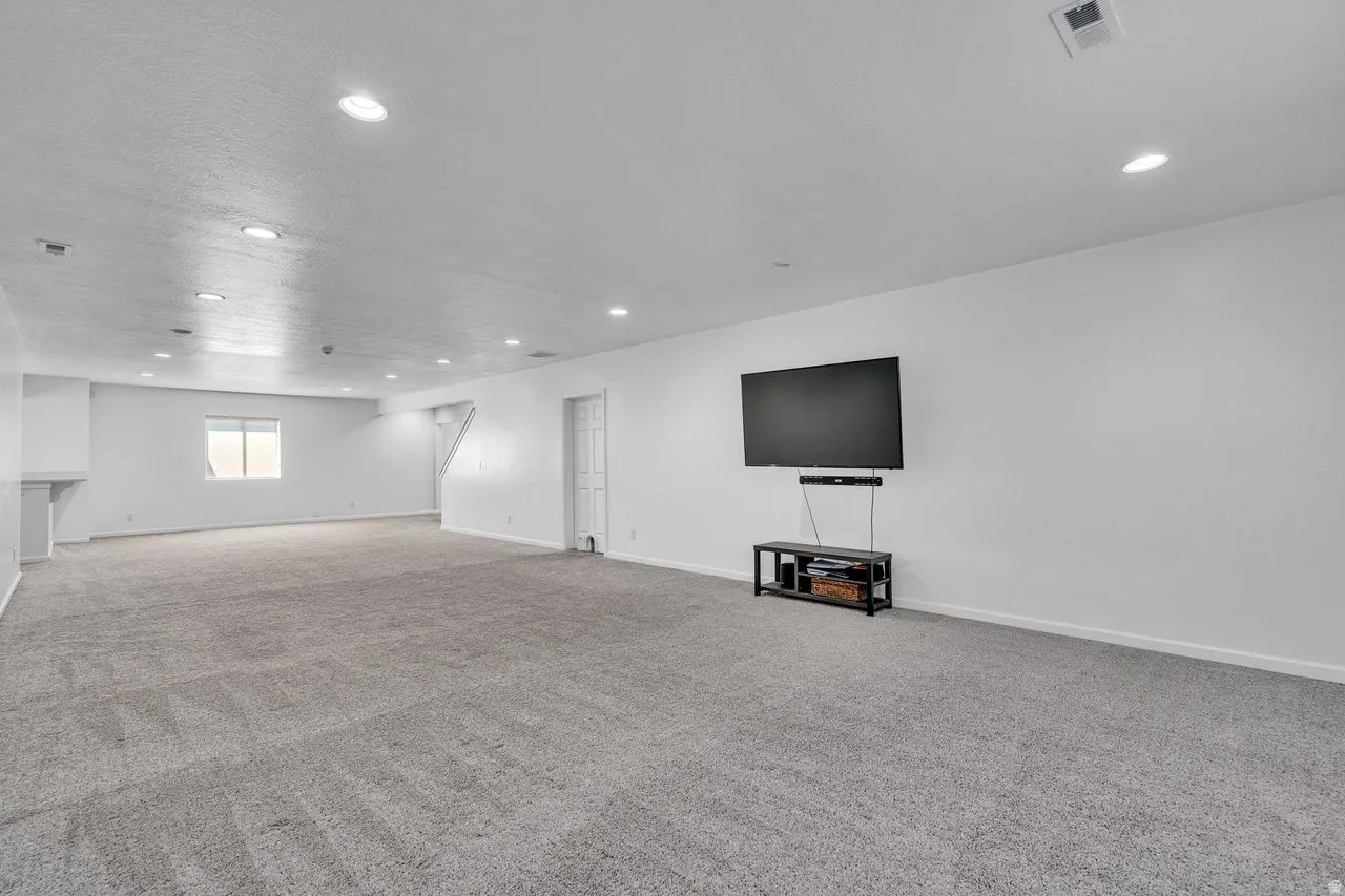 Expansive recreation room featuring gray carpet, recessed lighting, a single window, and a white interior door