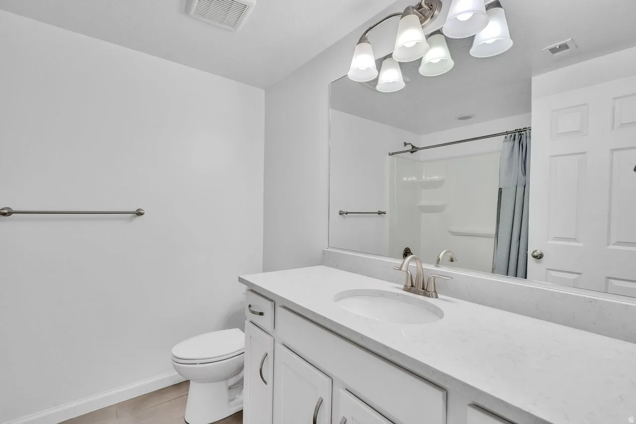Bathroom vanity featuring a single basin, brushed nickel faucet, and a light-toned countertop