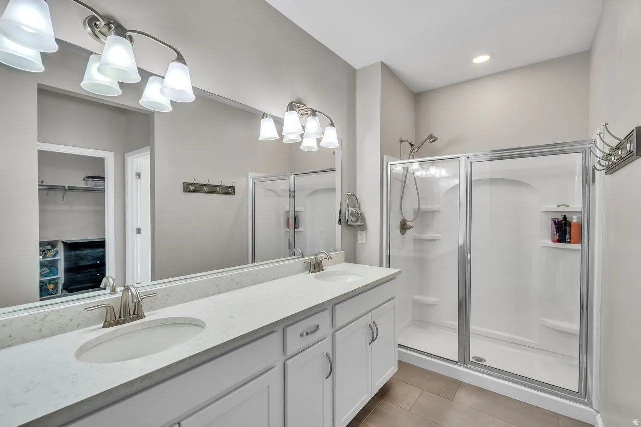 Bathroom featuring a dual vanity with undermount sinks, stone countertops, and white cabinetry