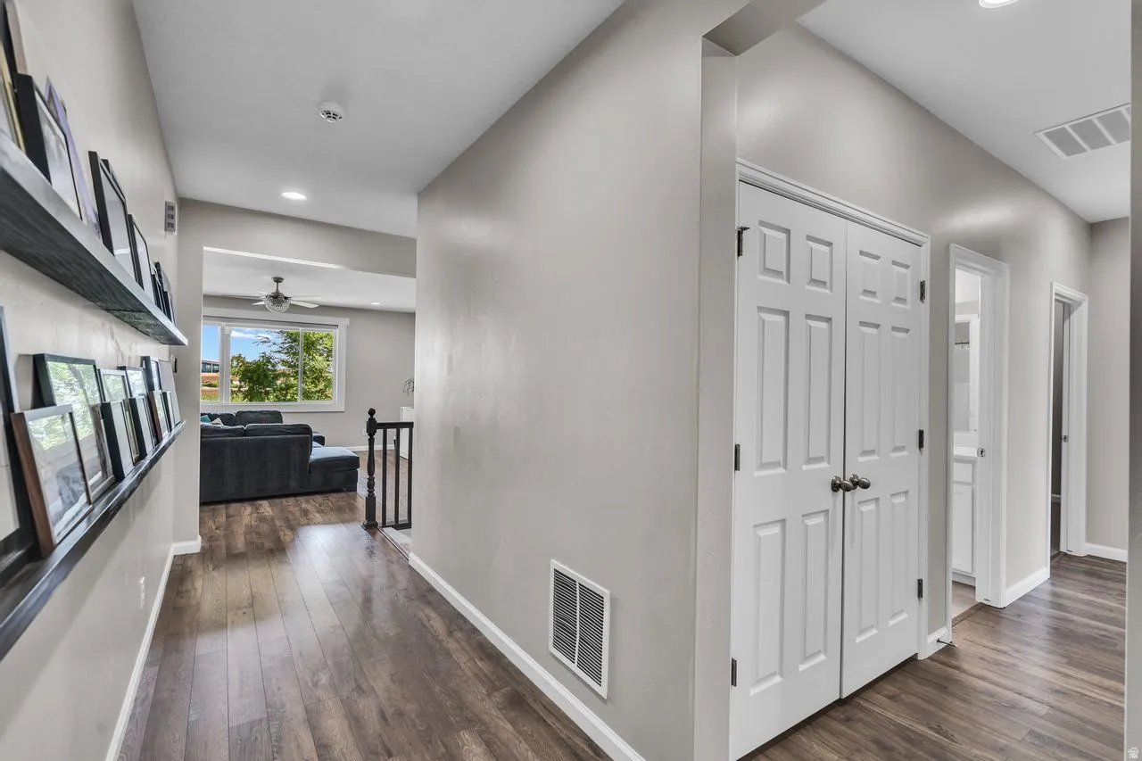 Hallway featuring wood-finish flooring, light grey wall paint, and white trim