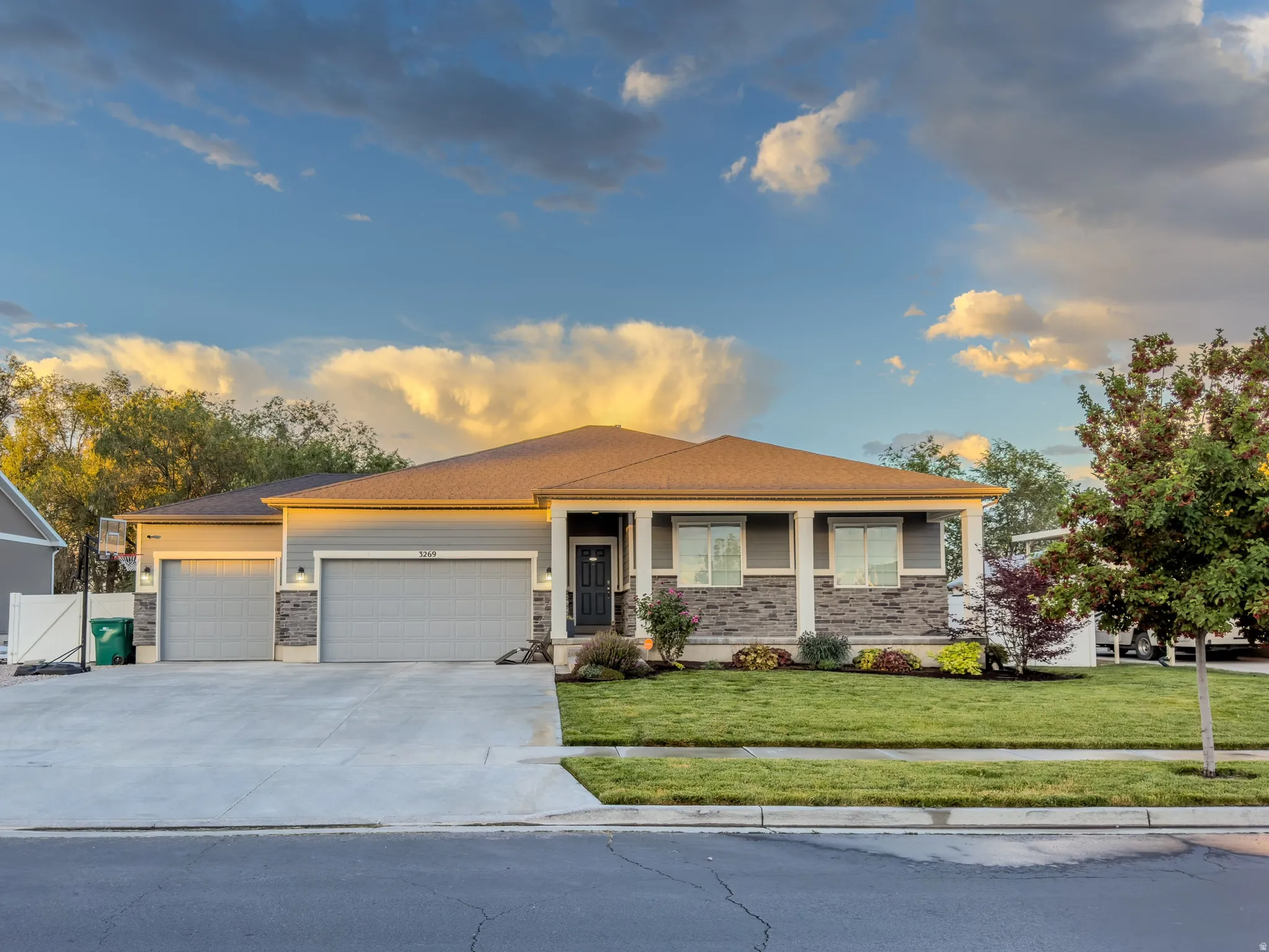Ranch-style residence featuring a gray exterior with stone accents and a covered front porch