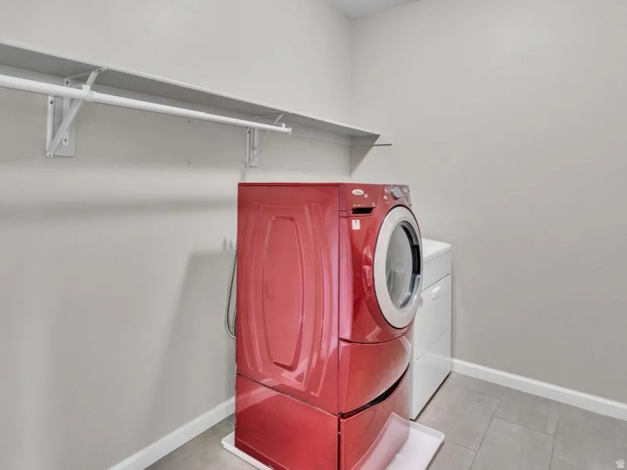 Dedicated utility room featuring gray walls, overhead shelving, and tile flooring