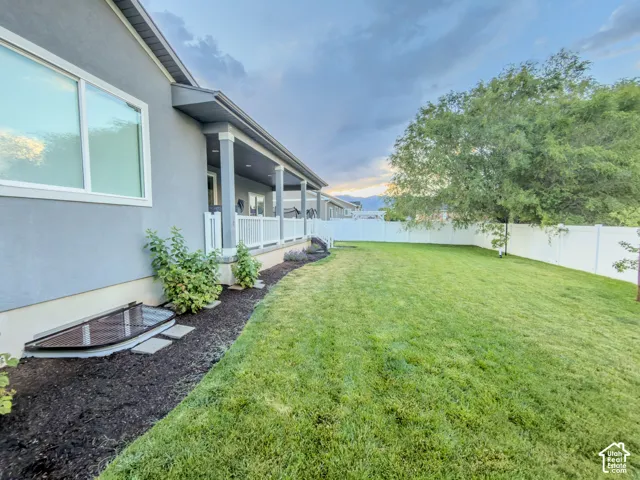 Expansive backyard featuring a manicured lawn, a large mature tree, and a white vinyl privacy fence