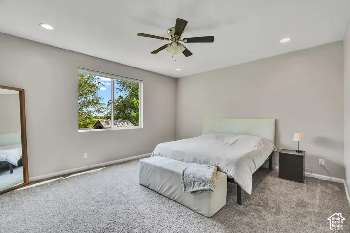 Carpeted room with a large window, recessed lighting, and a ceiling fan
